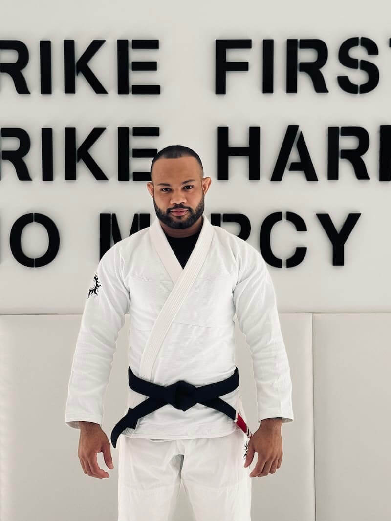 BLITZ Sun & Moon Brazilian Jiu-Jitsu Gi showcased by a practitioner in front of motivational training wall.