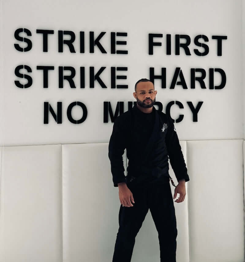 Man wearing BLITZ Sun & Moon Brazilian Jiu-Jitsu Gi standing against a motivational wall.