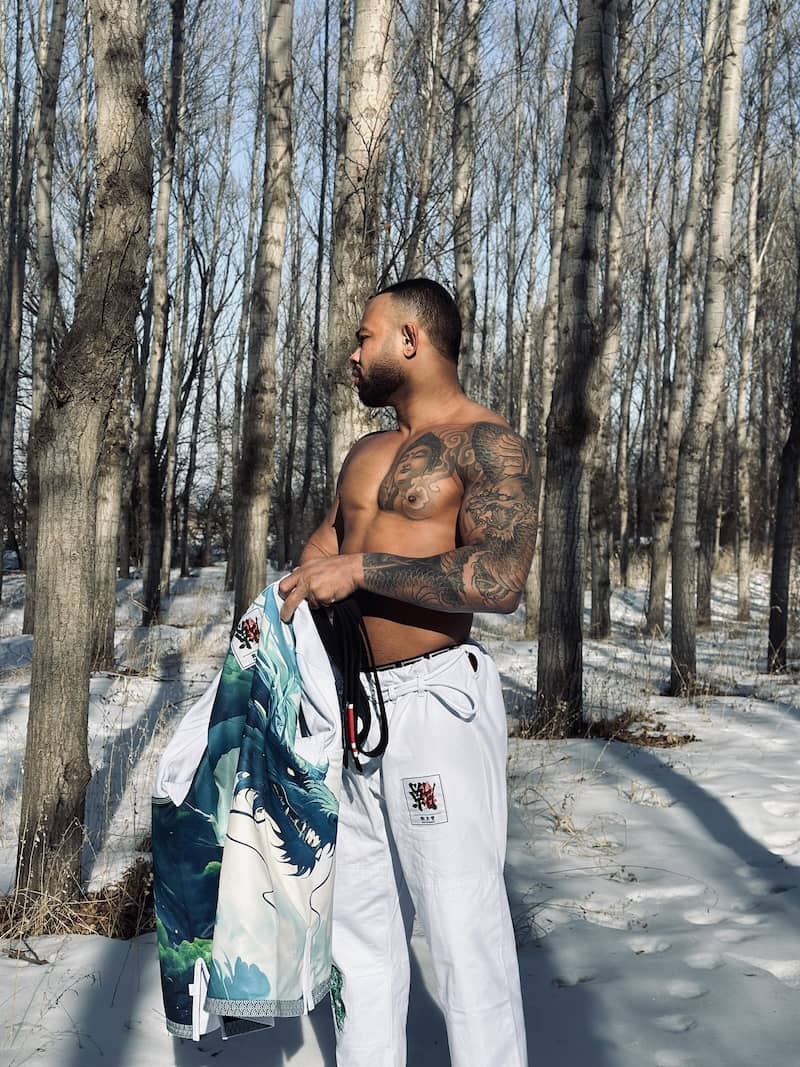 Model showcasing ZHAN Year of the Dragon Limited Edition BJJ Gi in snowy forest setting.