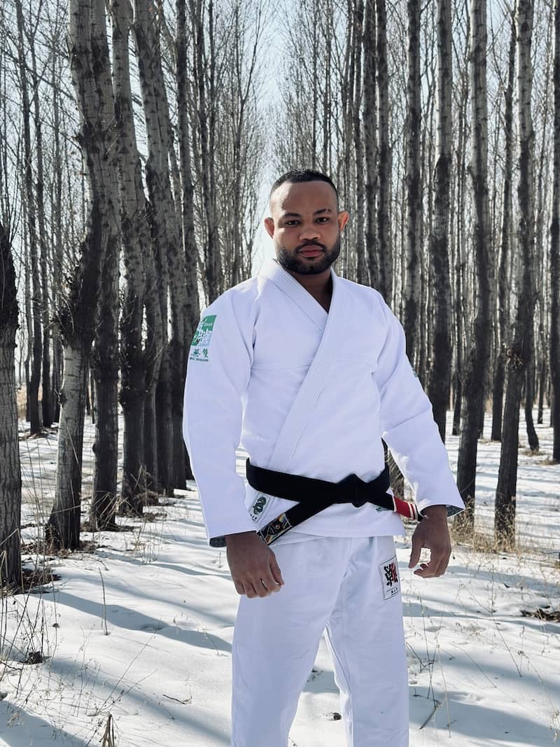 A martial artist wearing ZHAN Year of the Dragon Limited Edition BJJ Gi in a snowy forest setting.