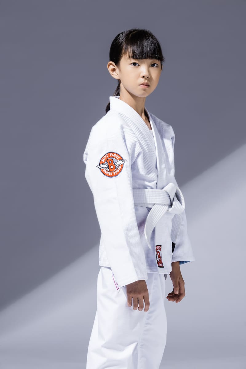 A young girl wearing the BLITZ Kids Super Power BJJ Gi, showcasing comfort and style for Brazilian Jiu-Jitsu training.