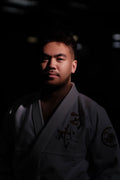 A person wearing a ZHAN Black Tortoise BJJ Gi stands in a dark setting, showcasing the gi's detail and design.