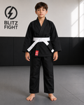 A child wearing the BLITZ Kids Basic BJJ Gi with a white belt, standing on a mat in a training space.