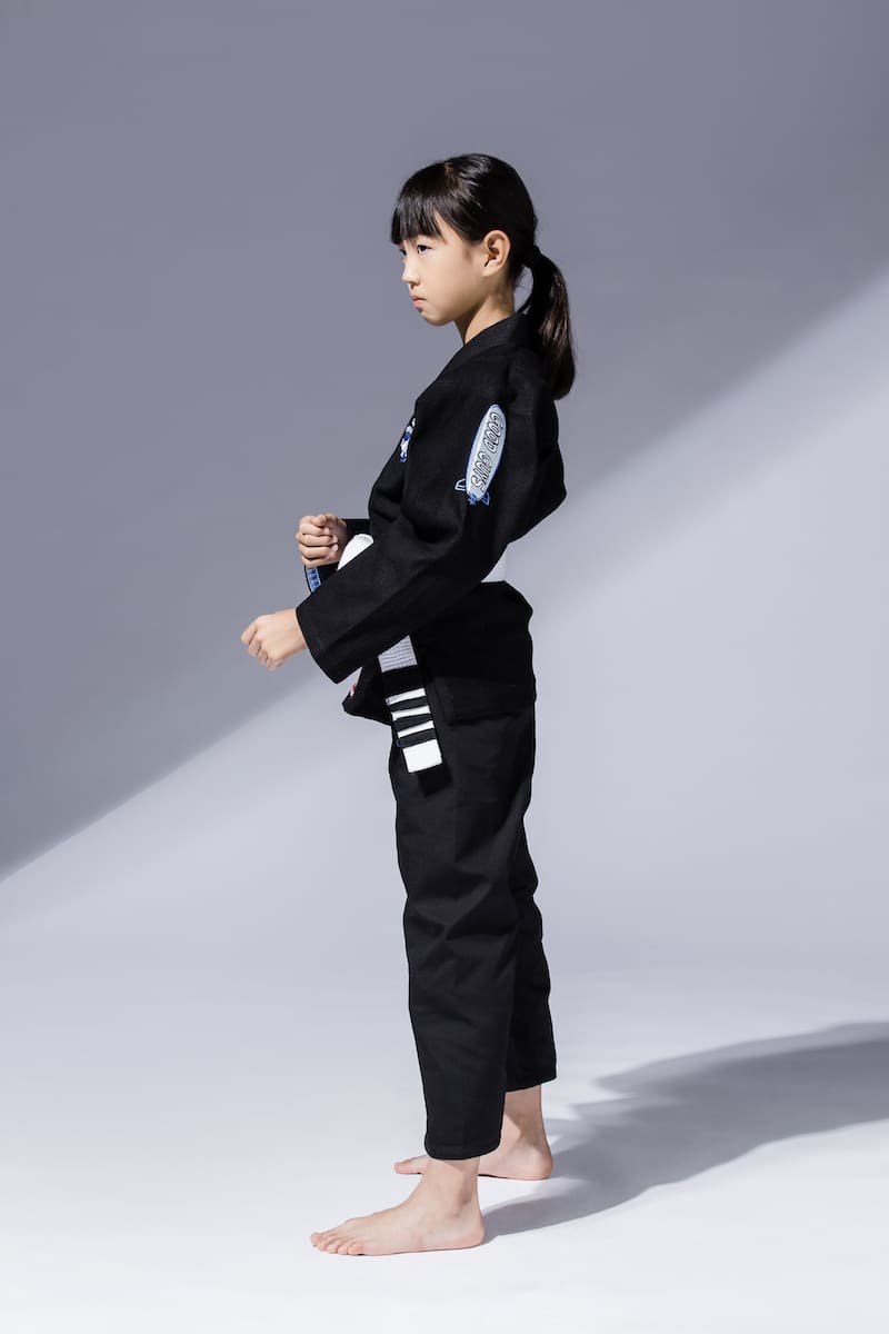 BLITZ Kids Super Power BJJ Gi on a young athlete demonstrating a side pose, showcasing comfort and durability.