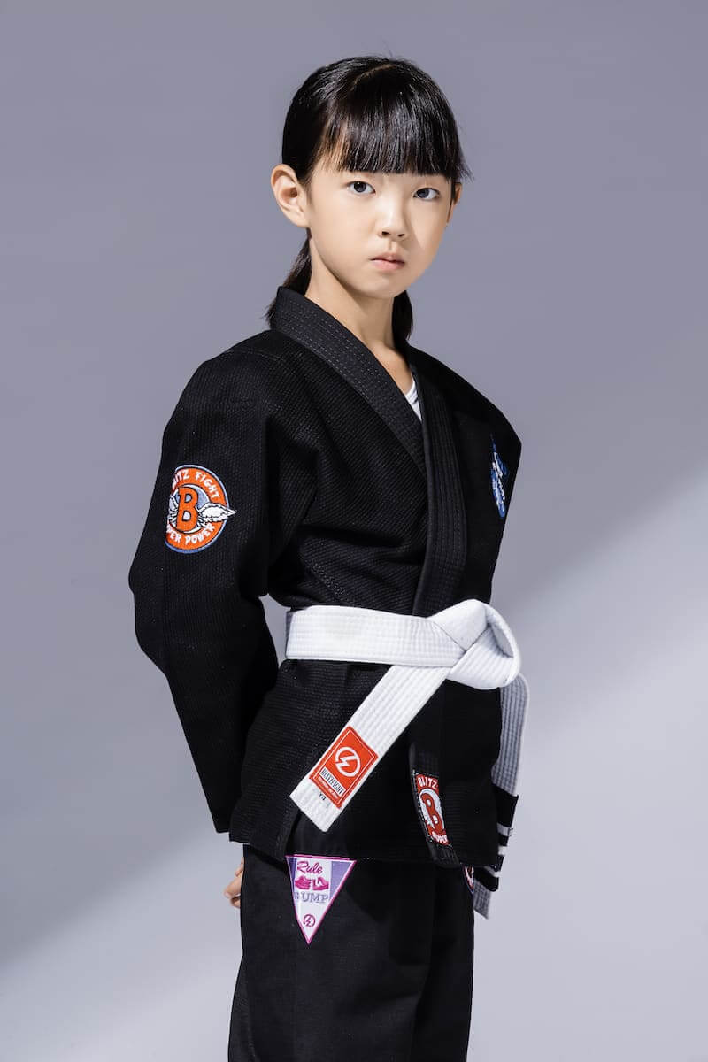 BLITZ Kids Super Power BJJ Gi worn by a young girl, showcasing comfort and style for Brazilian Jiu-Jitsu training.