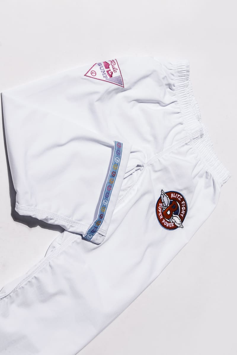 BLITZ Kids Super Power BJJ Gi featuring fun embroidered patches on white fabric for young athletes.