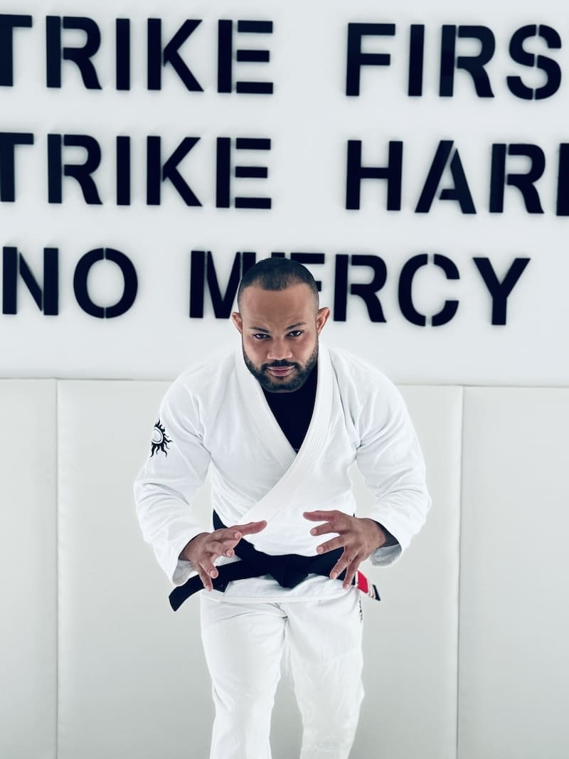 Athlete in BLITZ Sun & Moon Brazilian Jiu-Jitsu Gi preparing for training, with motivational text in the background.