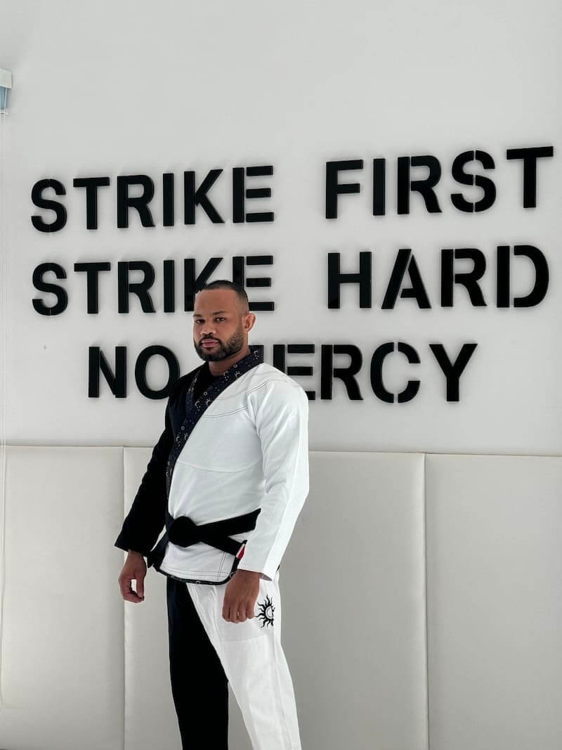 Trainer wearing a BLITZ Sun & Moon Brazilian Jiu-Jitsu Gi against a motivational wall.