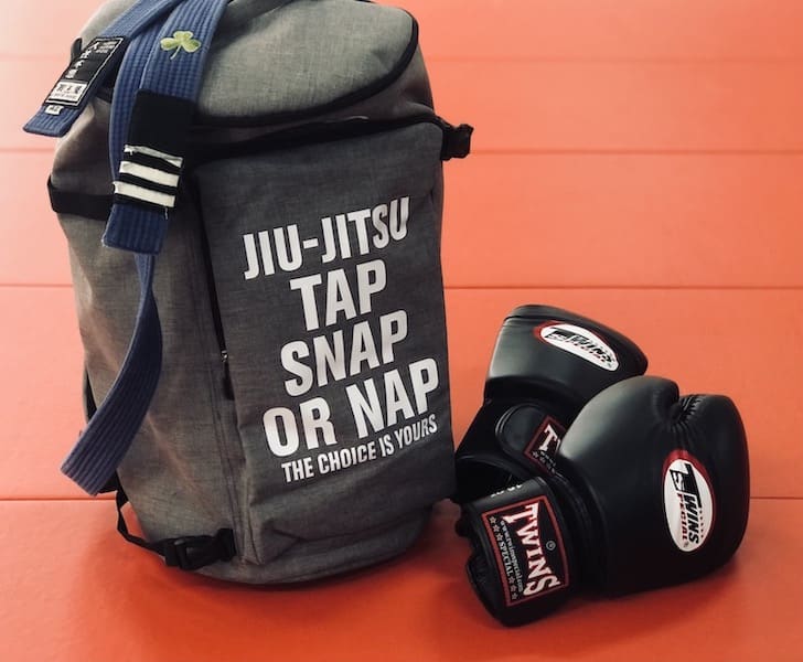 Ultimate BJJ Backpack: Spacious & Durable Gear Bag for Martial Artists with boxing gloves on mat.