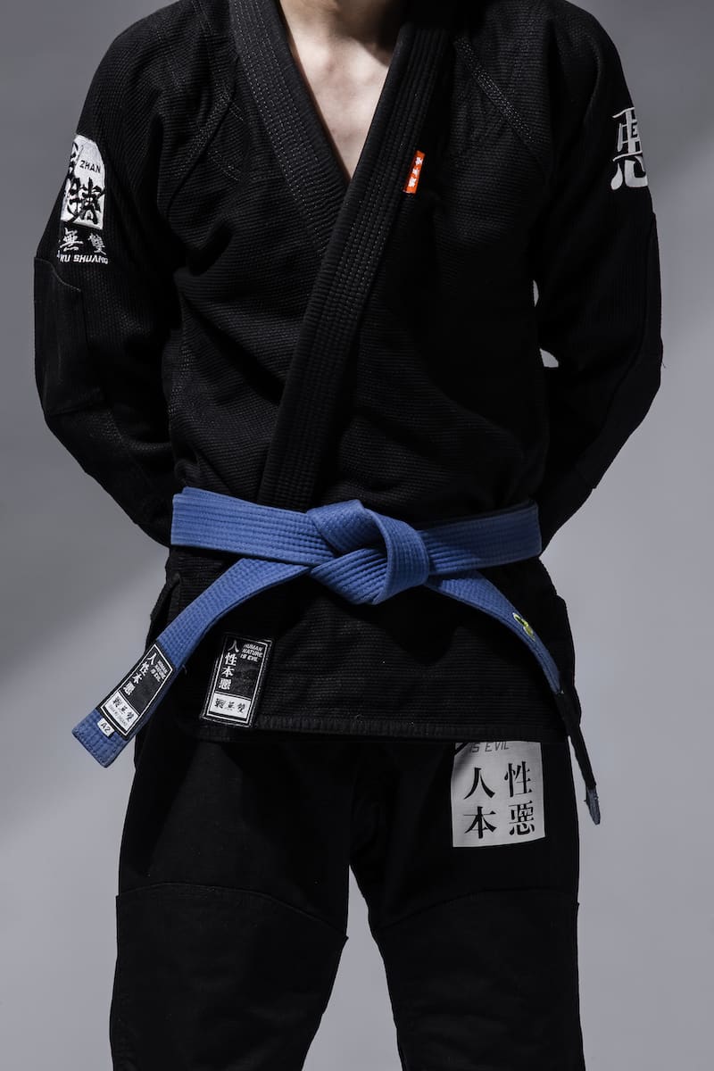 ZHAN Good vs Evil BJJ Gi showcasing black fabric with blue belt and detailed embroidery.