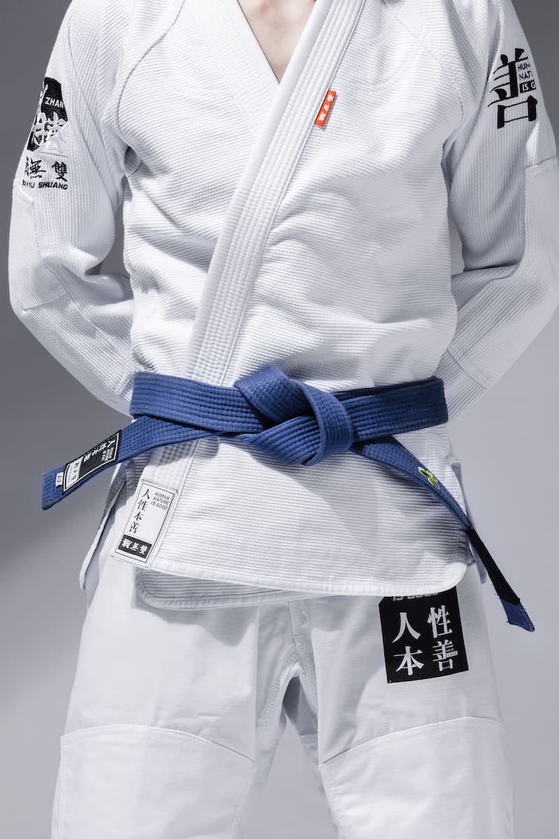ZHAN Good vs Evil BJJ Gi showcased with blue belt, highlighting the contrast between good and evil in Brazilian Jiu-Jitsu.