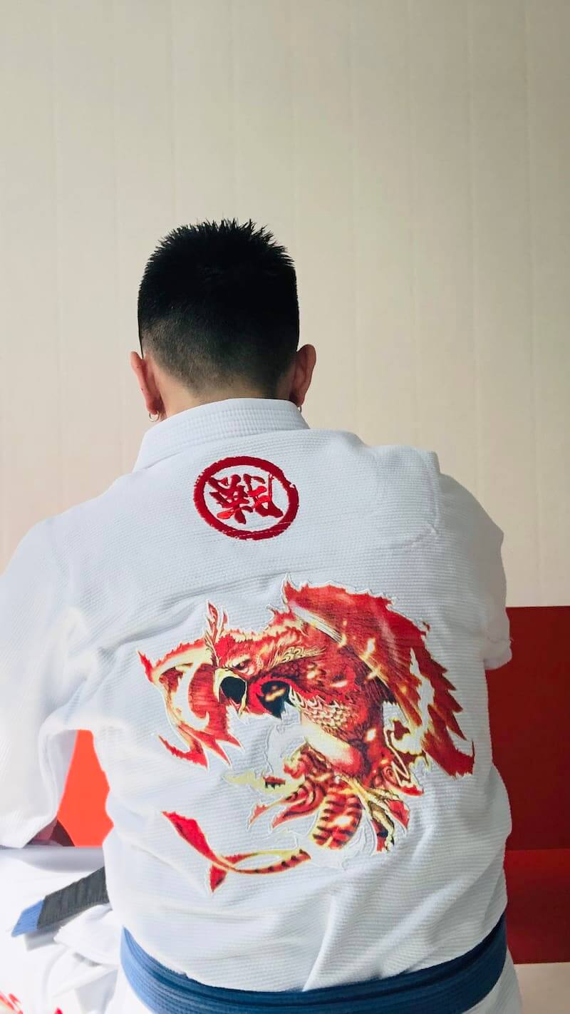 Back view of a person wearing the ZHAN Vermilion Phoenix BJJ Gi featuring vibrant phoenix embroidery.